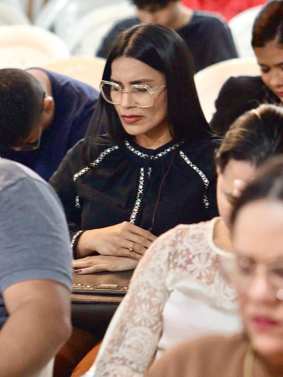 Mulher de óculos em oração, de cabeça baixa, durante um culto da MUP
